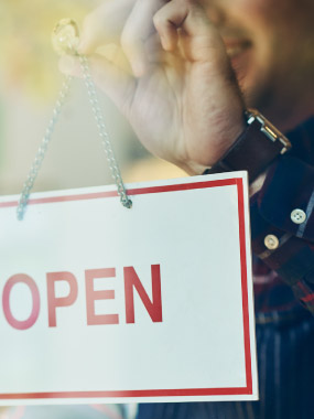 Man holding up "open" sign in business window