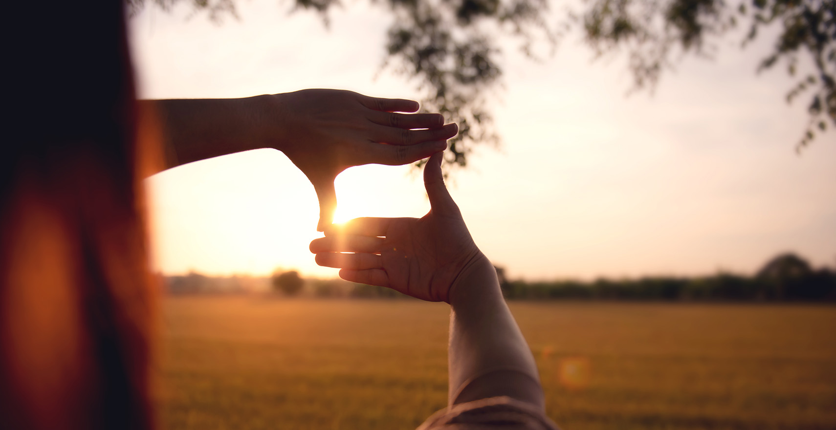 hands framing a sunset 